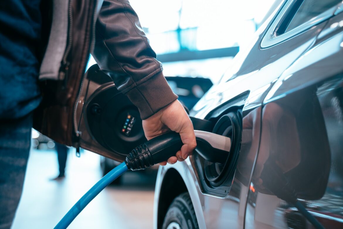 Man holding the charging cable to charge an electric car representing the advantages of electric car