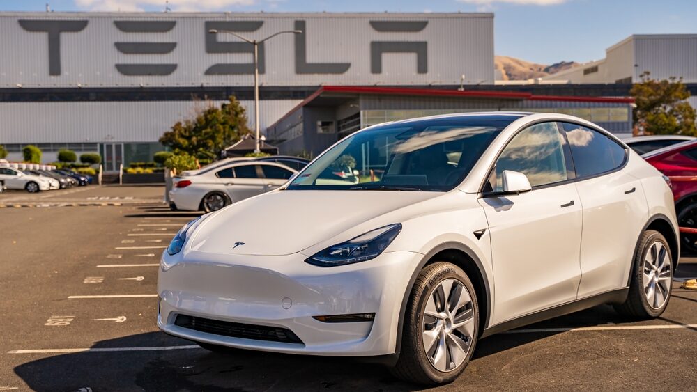 Tesla model 3 parked in front of giant TESLA billbaord