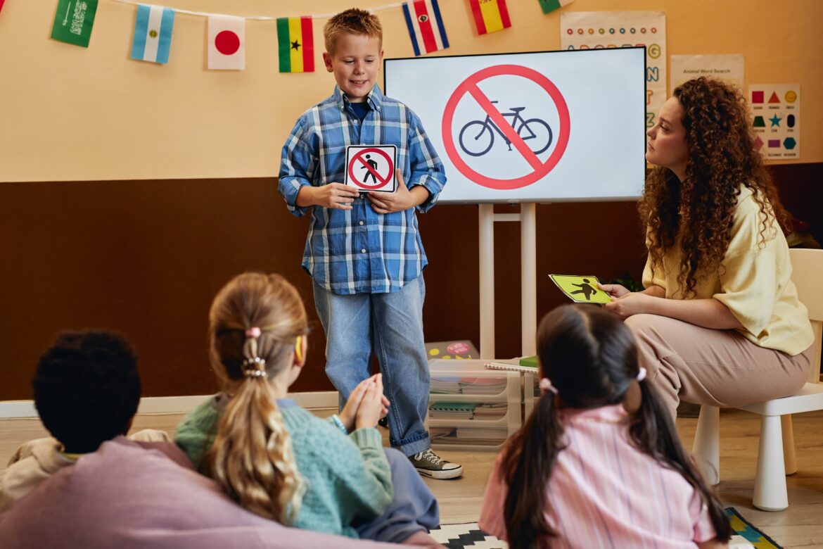 smiling young boy holding No walking sign while presenting road safety rules to kids in school classroom copy space